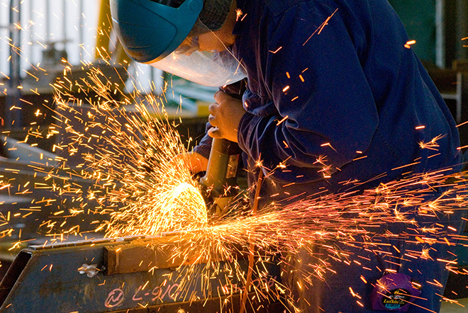 Industriel - Balance industrielle d’un homme meulant une pièce métallique